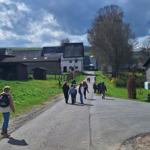 Kinder mit Rucksäcken wandern von hinten den Hügel hinab.